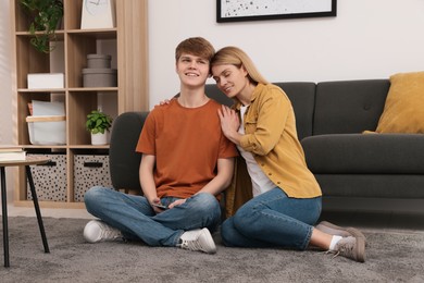 Photo of Happy mother and her teenage son spending time together on floor at home
