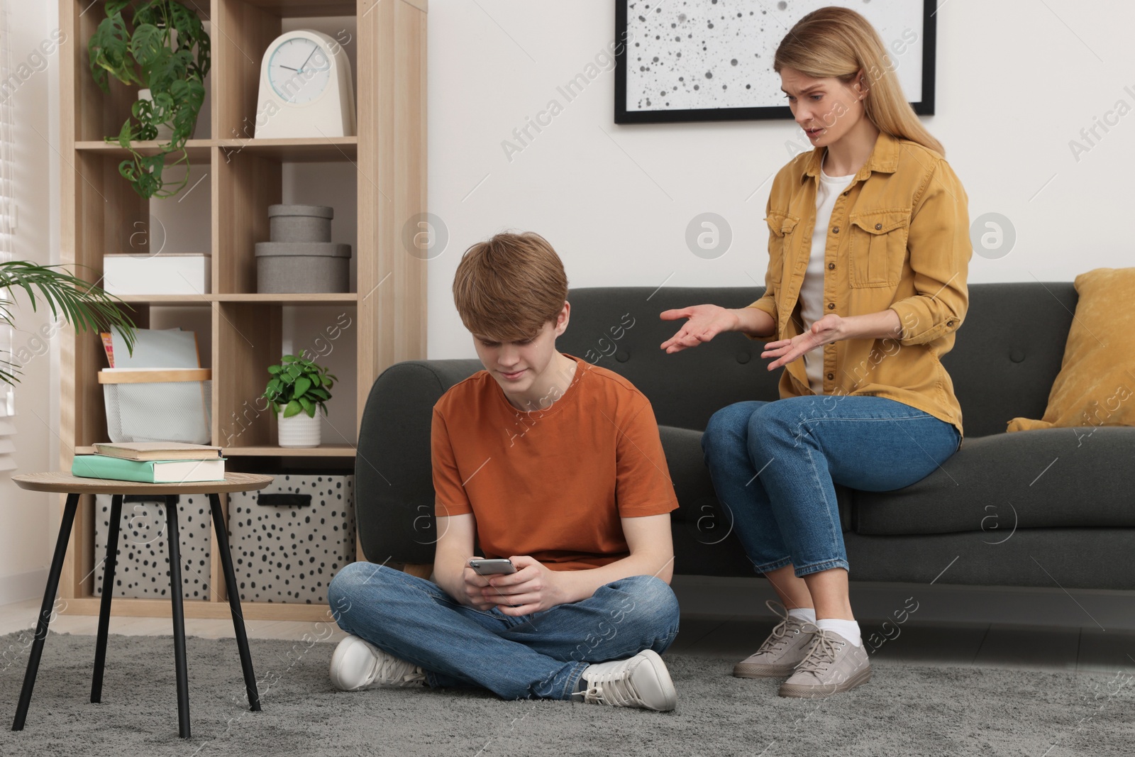 Photo of Teenage son with smartphone ignoring his mother at home