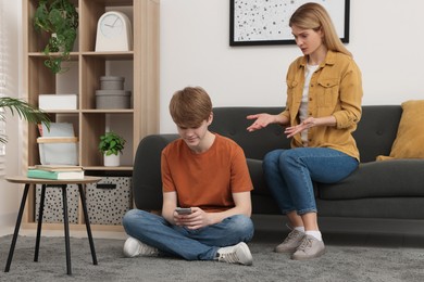 Photo of Teenage son with smartphone ignoring his mother at home