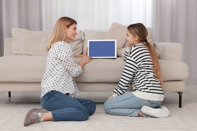 Photo of Happy mother and her teenage daughter with laptop on floor at home