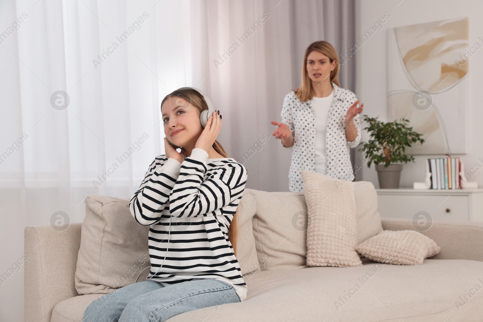 Photo of Teenage daughter with headphones ignoring her mother at home