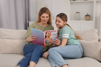 Photo of Happy mother and her teenage daughter spending time together with magazine at home