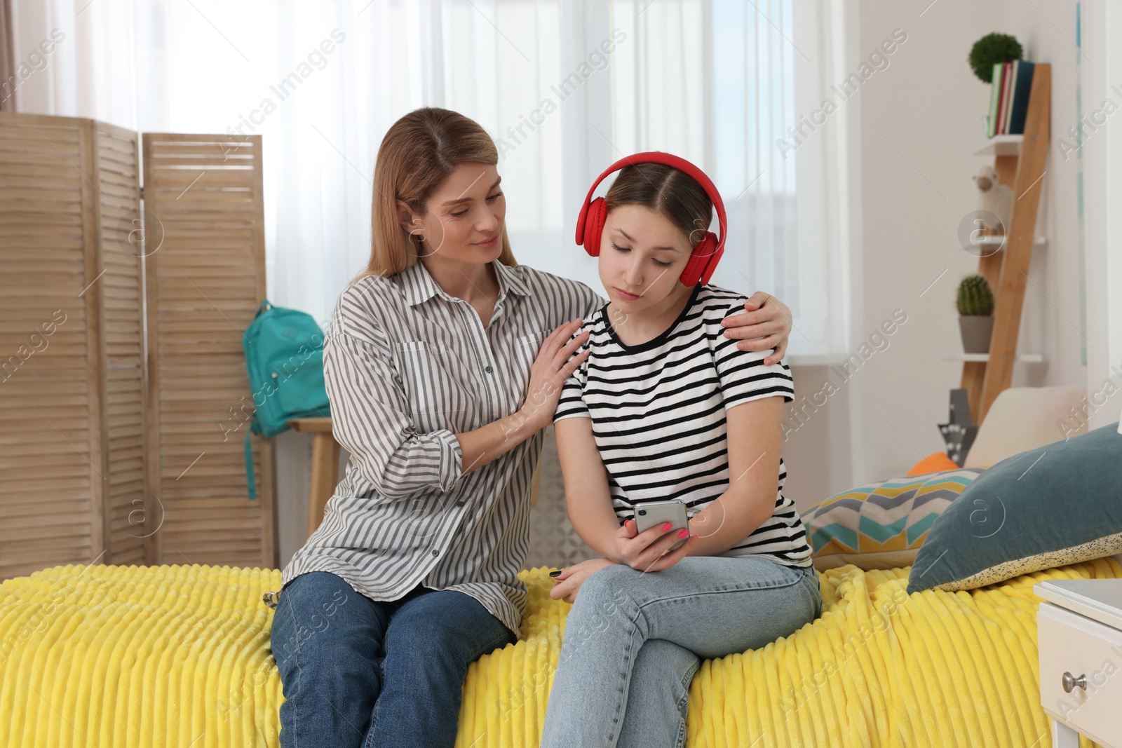 Photo of Mother comforting her upset teen daughter with headphones at home