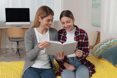 Photo of Happy mother and her teenage daughter spending time together with book at home