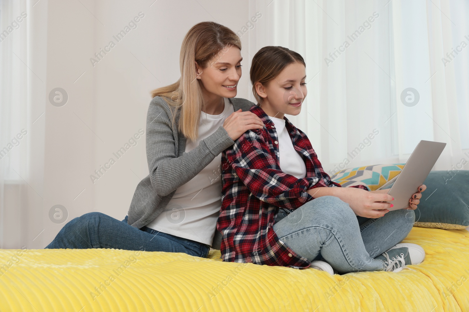 Photo of Happy mother and her teenage daughter with laptop at home