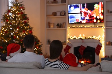 Photo of Family watching TV in cosy room, back view. Christmas atmosphere