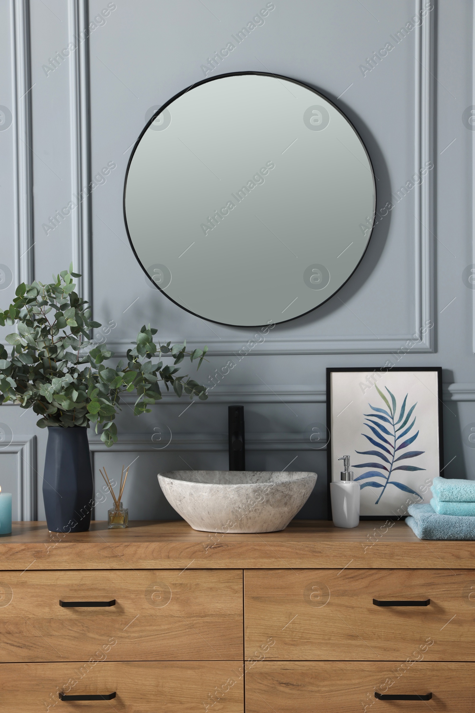 Photo of Stylish mirror over vessel sink, towels and eucalyptus branches on bathroom vanity. Interior design