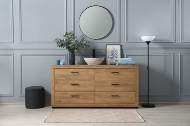 Photo of Modern bathroom interior with stylish mirror, eucalyptus branches, vessel sink and wooden vanity