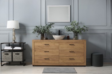 Photo of Modern bathroom interior with stylish mirror, eucalyptus branches, vessel sink and wooden vanity