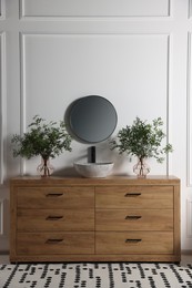 Photo of Modern bathroom interior with stylish mirror, eucalyptus branches, vessel sink and wooden vanity