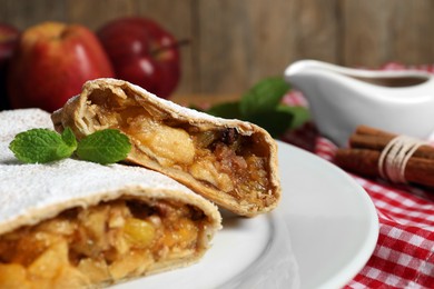 Photo of Delicious strudel with apples, nuts and raisins on wooden table, closeup