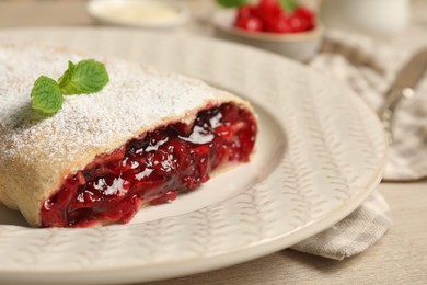 Photo of Delicious strudel with cherries, powdered sugar and mint on white wooden table, closeup
