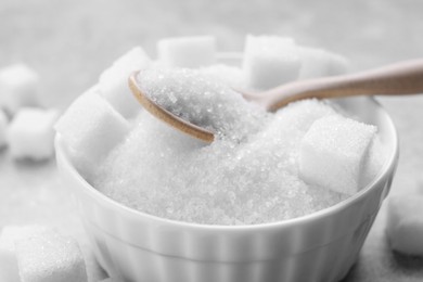 Different types of white sugar in bowl on grey table, closeup