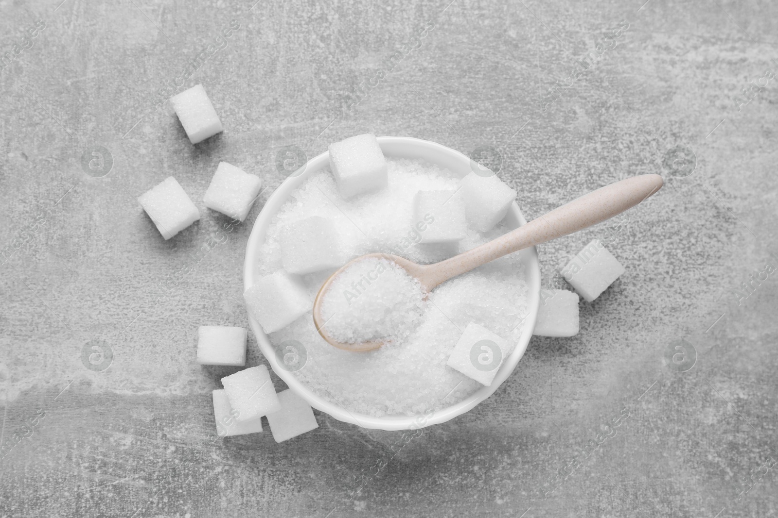 Photo of Different types of white sugar on grey table, flat lay