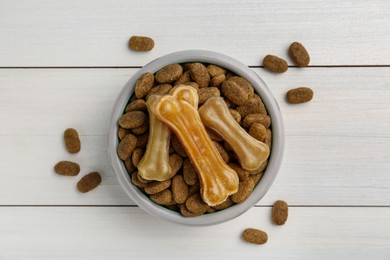 Dry dog food and treats (chew bones) on white wooden floor, flat lay