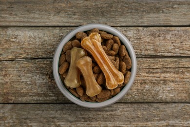 Dry dog food and treats (chew bones) on wooden floor, top view