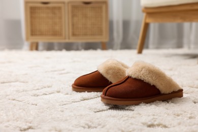 Photo of Slippers on soft white carpet in living room. Space for text