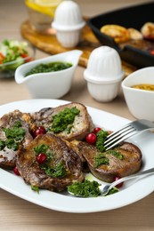 Tasty beef tongue pieces, salsa verde and berries on beige wooden table, closeup