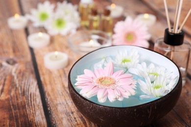 Photo of Bowl with water and beautiful flowers on wooden table, space for text. Spa composition