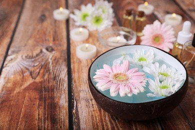 Bowl with water and beautiful flowers on wooden table, space for text. Spa composition