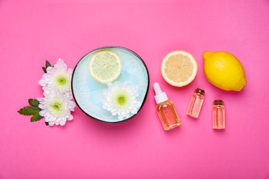 Photo of Flat lay composition with bowl of water, flowers and lemons on pink background. Spa treatment