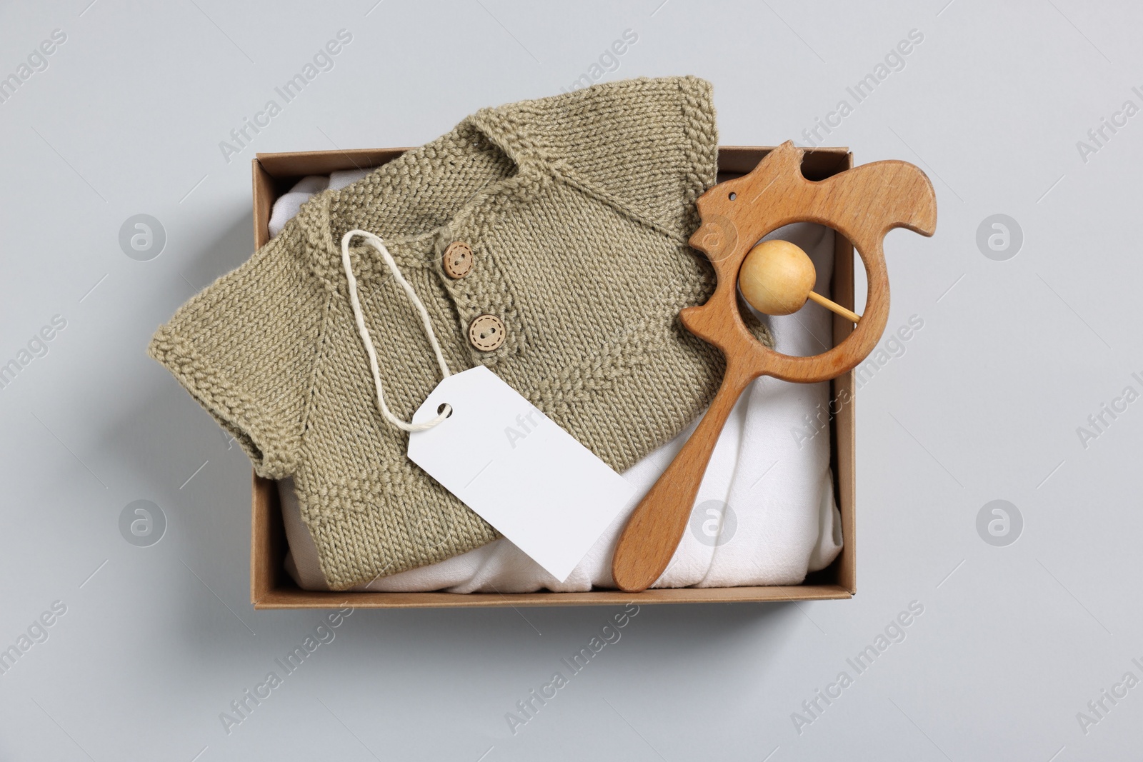 Photo of Different baby accessories, clothes and blank card in box on light grey background, top view