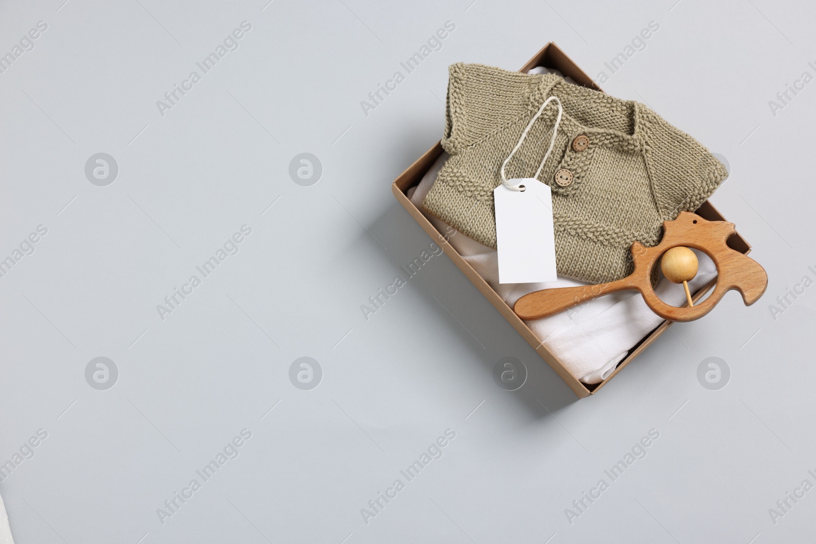 Photo of Different baby accessories, clothes and blank card in box on light grey background, top view. Space for text