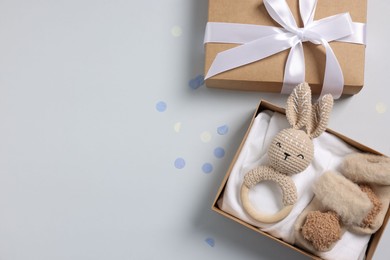 Photo of Different baby accessories in box and confetti on light grey background, flat lay. Space for text