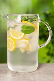 Freshly made lemonade with mint in jug on grey table outdoors