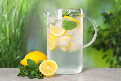 Freshly made lemonade with mint in jug on grey table outdoors