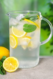 Photo of Freshly made lemonade with mint in jug on grey table outdoors