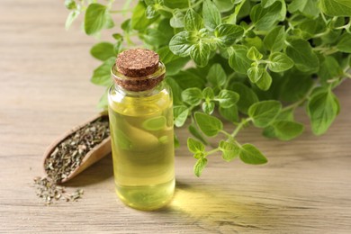 Photo of Essential oil in bottle, scoop with dry herb and oregano leaves on wooden table, closeup