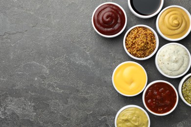 Photo of Many different sauces in bowls on grey table, top view. Space for text