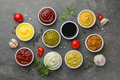 Photo of Many different sauces and spices on grey table, flat lay