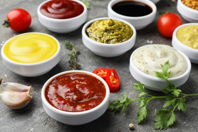 Photo of Many different sauces and spices on grey table, closeup