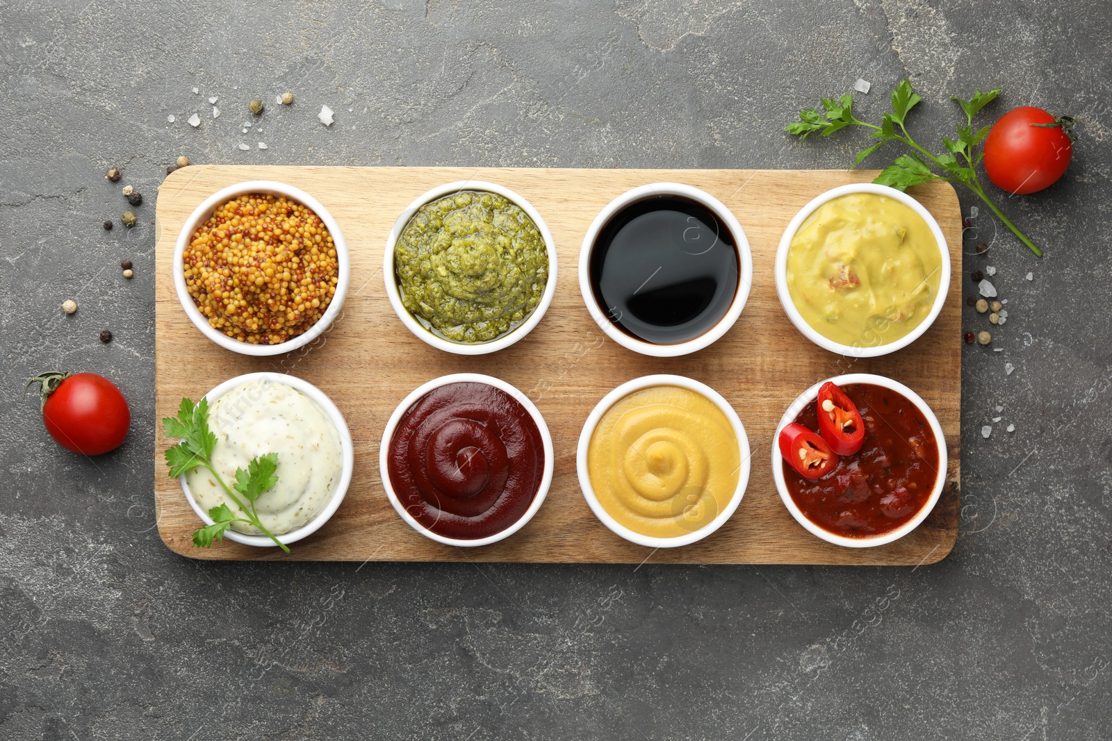 Photo of Many different sauces and spices on grey table, flat lay