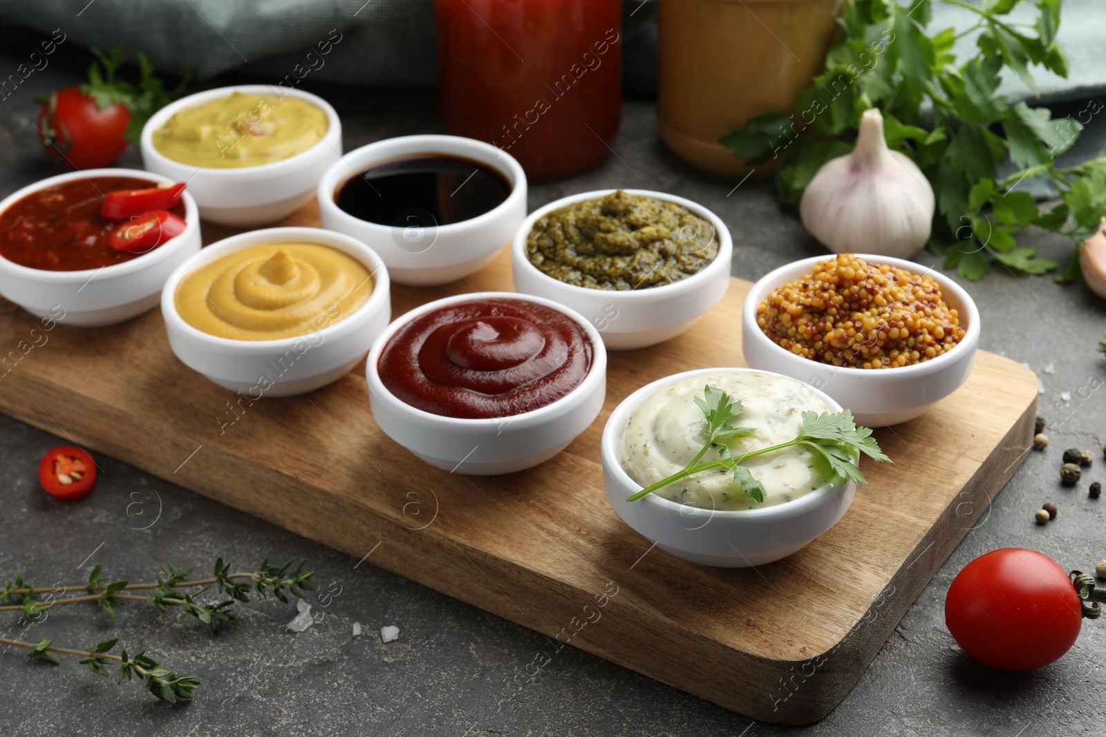 Photo of Many different sauces and products on grey table