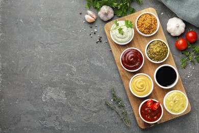 Photo of Many different sauces and products on grey table, flat lay. Space for text