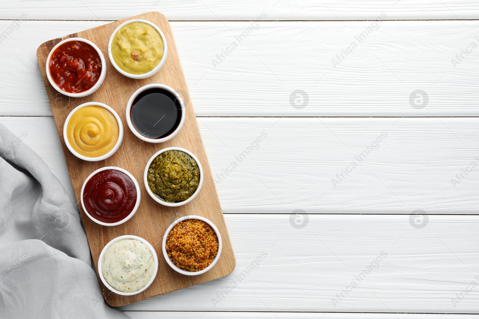 Photo of Many different sauces in bowls on white wooden table, top view. Space for text