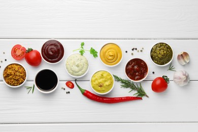 Photo of Many different sauces, spices and vegetables on white wooden table, flat lay