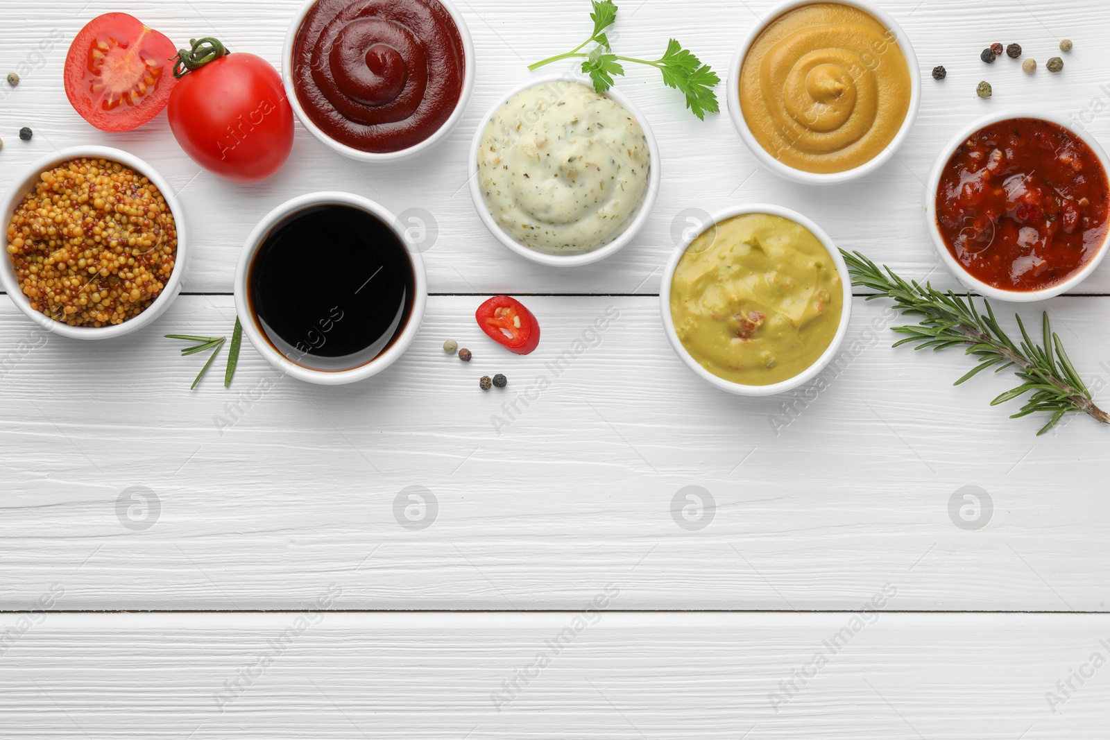 Photo of Many different sauces, spices and vegetables on white wooden table, flat lay. Space for text