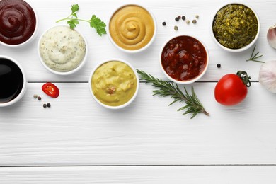 Photo of Many different sauces, spices and vegetables on white wooden table, flat lay. Space for text