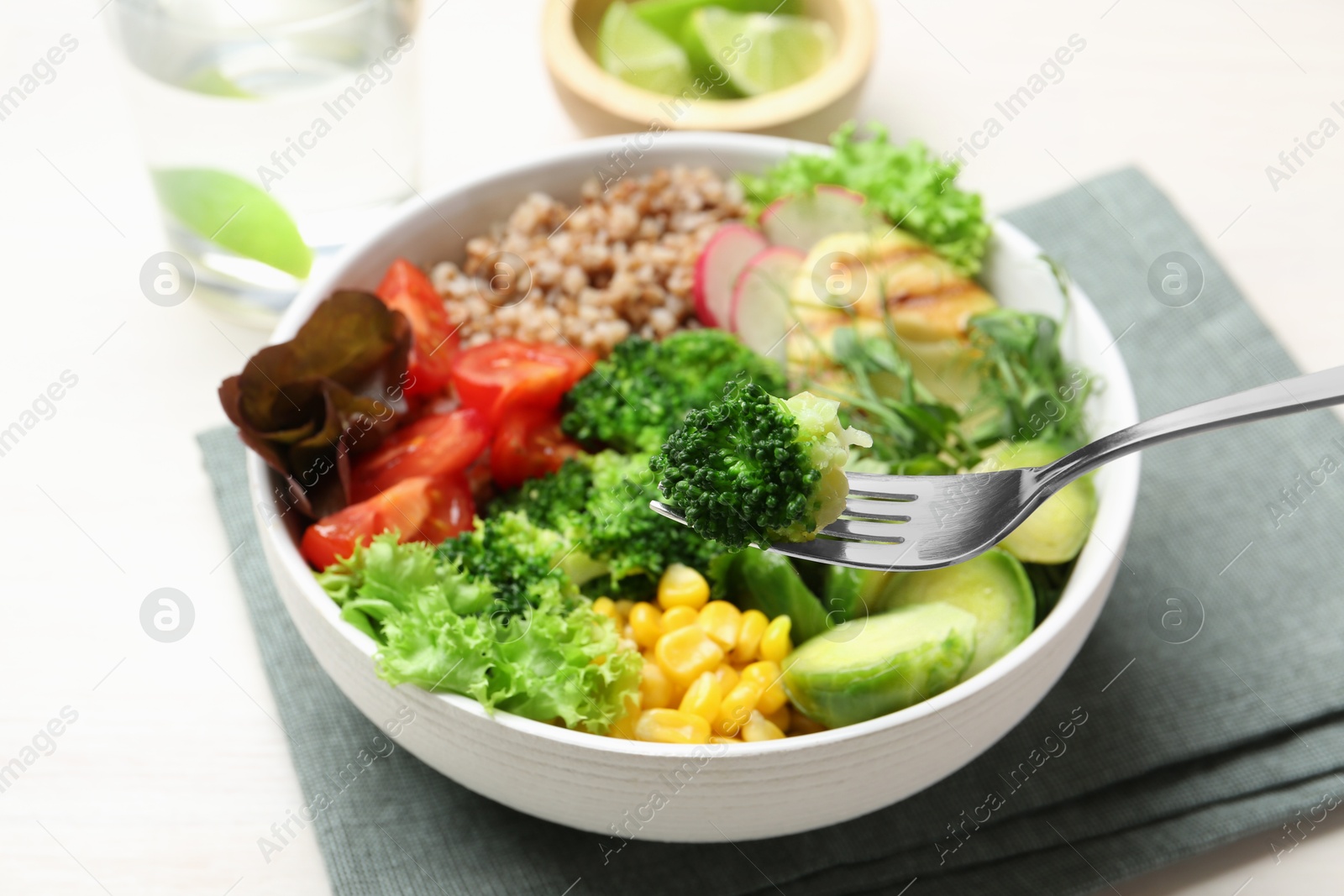 Photo of Healthy meal. Eating tasty products with fork from bowl on white table, closeup