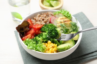 Photo of Healthy meal. Eating tasty products with fork from bowl on white table, closeup