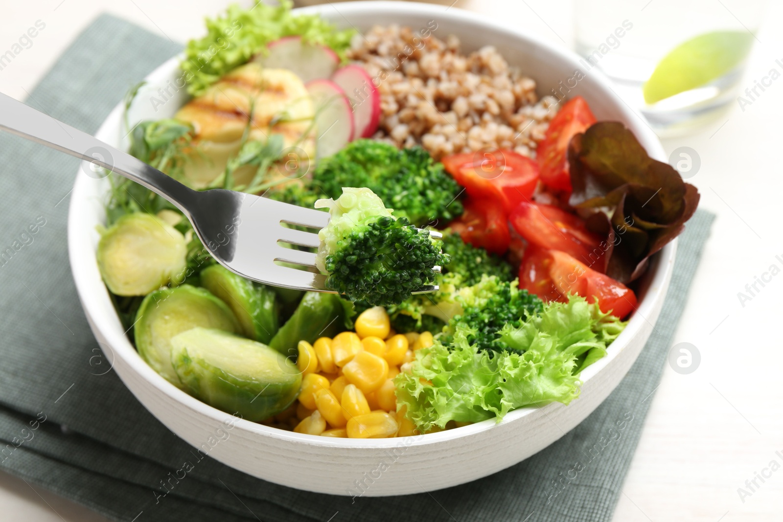 Photo of Healthy meal. Eating tasty products with fork from bowl on white table, closeup