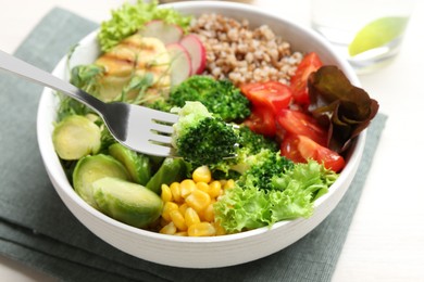 Photo of Healthy meal. Eating tasty products with fork from bowl on white table, closeup