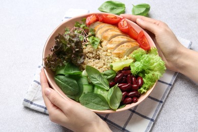 Healthy meal. Woman with bowl of tasty products at white table, closeup