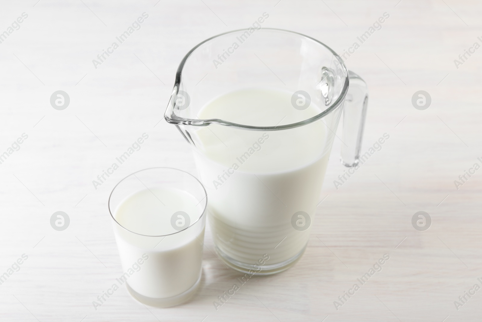 Photo of Jug and glass of fresh milk on wooden table