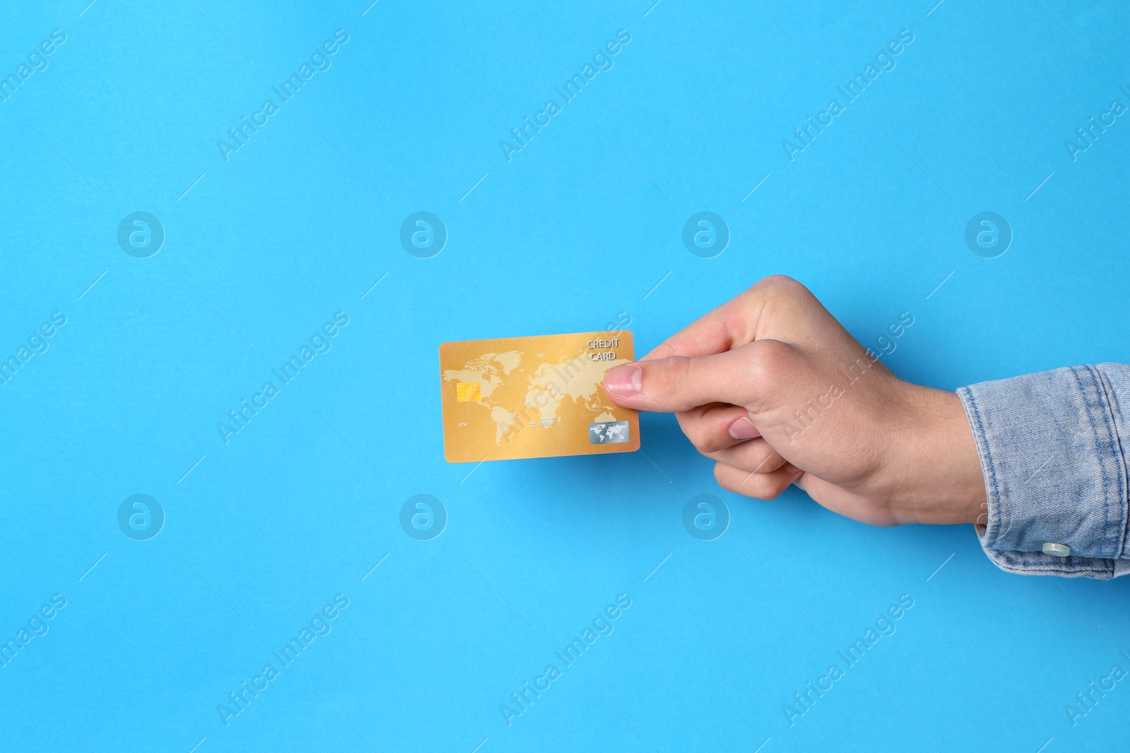 Photo of Man holding credit card on light blue background, closeup