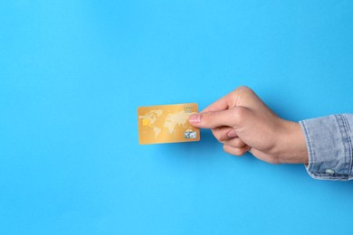 Man holding credit card on light blue background, closeup